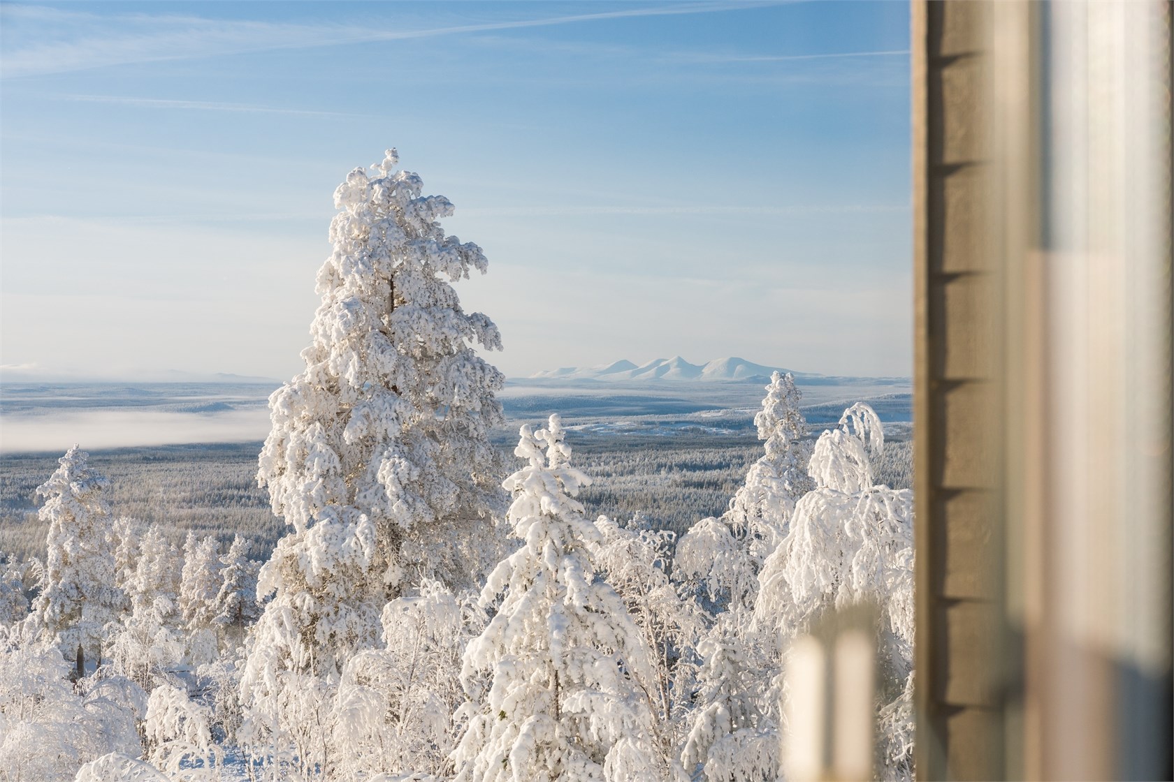Vinterutsikt över snötäckta fjäll och skog från lägenheten
